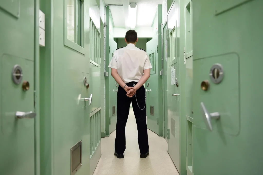 Prison officer walking in prison, being concerned about is personal safety, due to the daily threats of violence